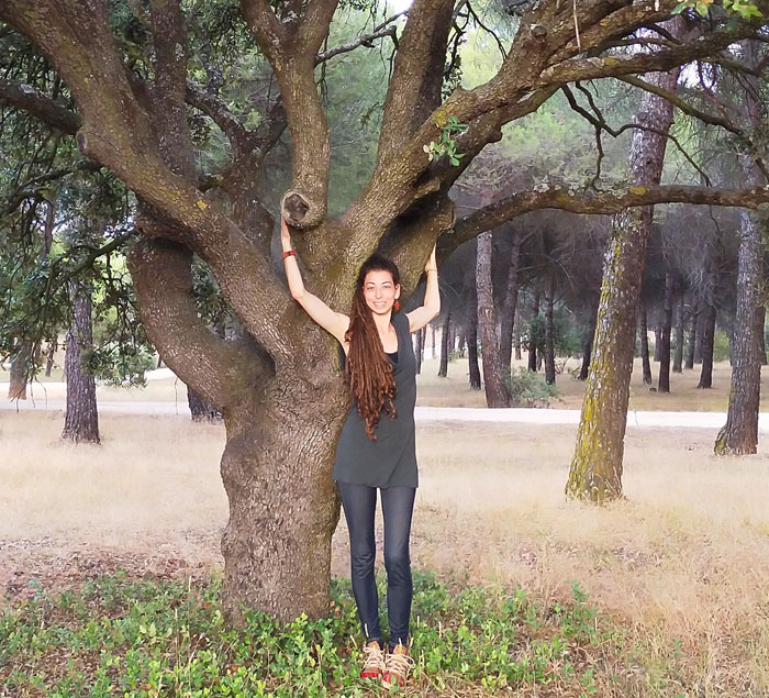 blanca martín de pie con los brazos en alto delante de un árbol, acompañamiento emocional con ecopsicología